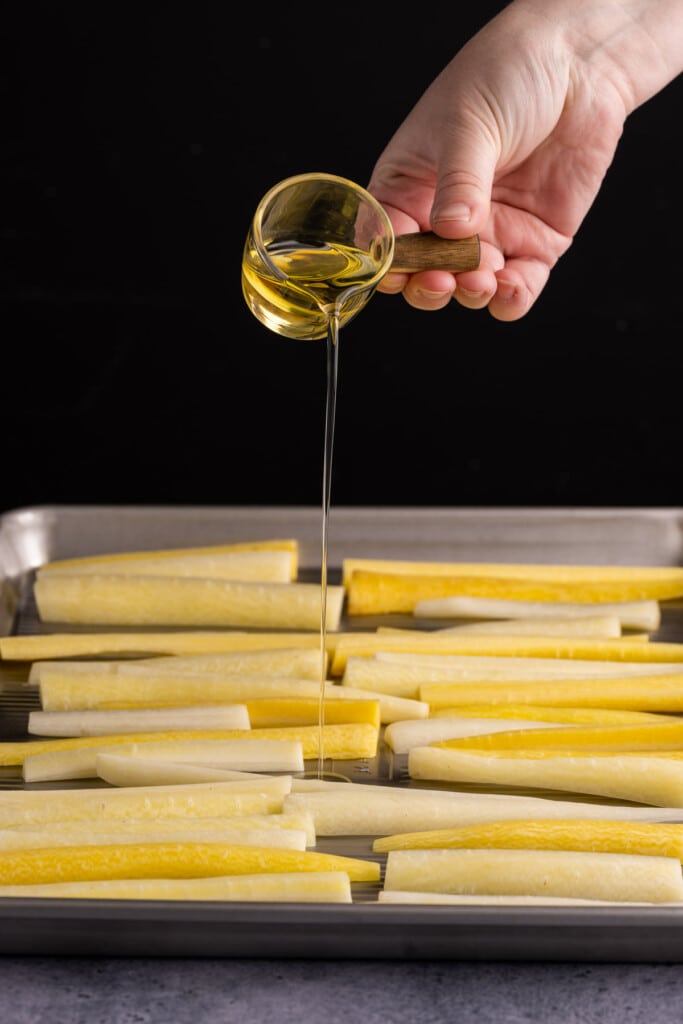 Adding olive oil to white carrots aka yellow carrots.