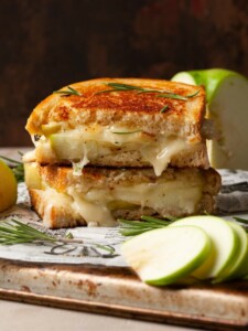 Brie and Apple Grilled Cheese Cut in Half and Stacked on a chopping board