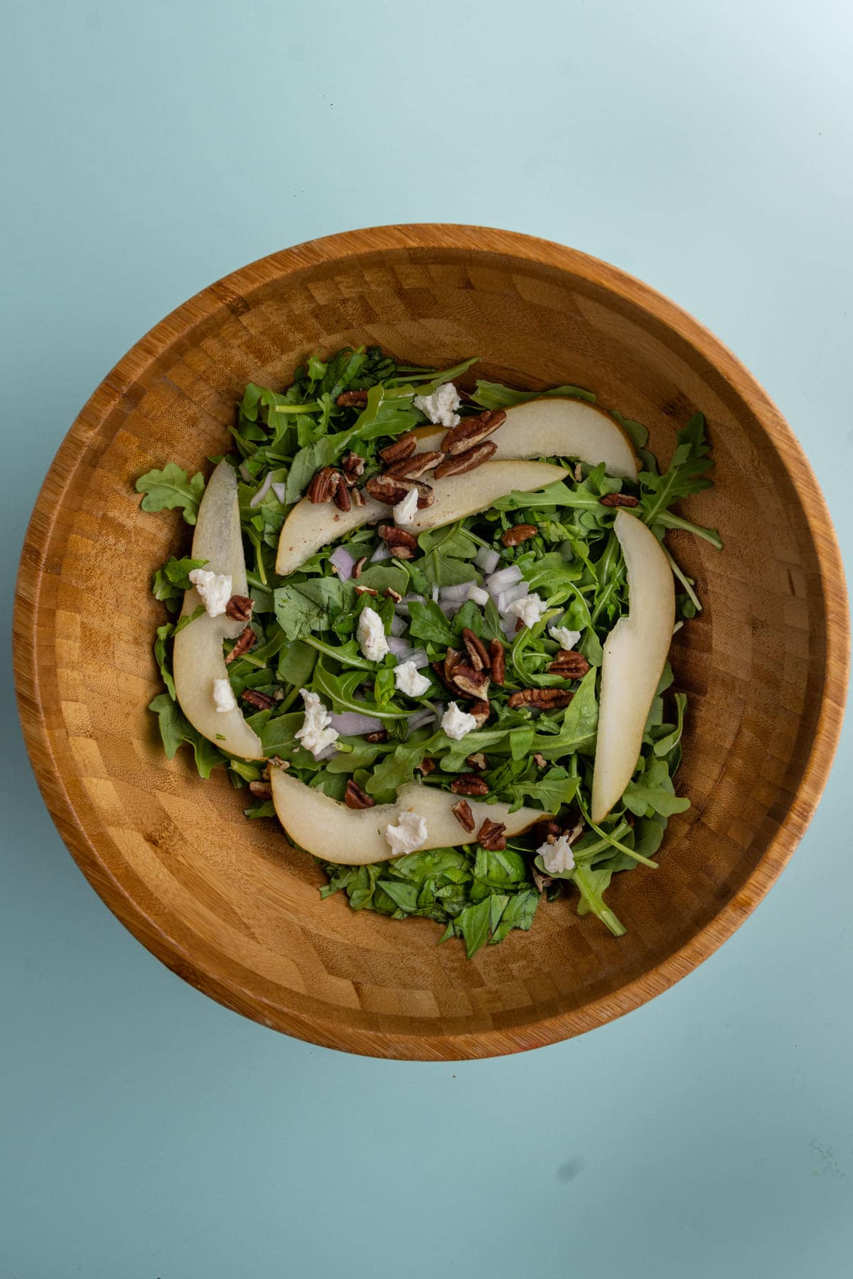 Mixing Pear and Arugula Salad ingredients in a large salad bowl