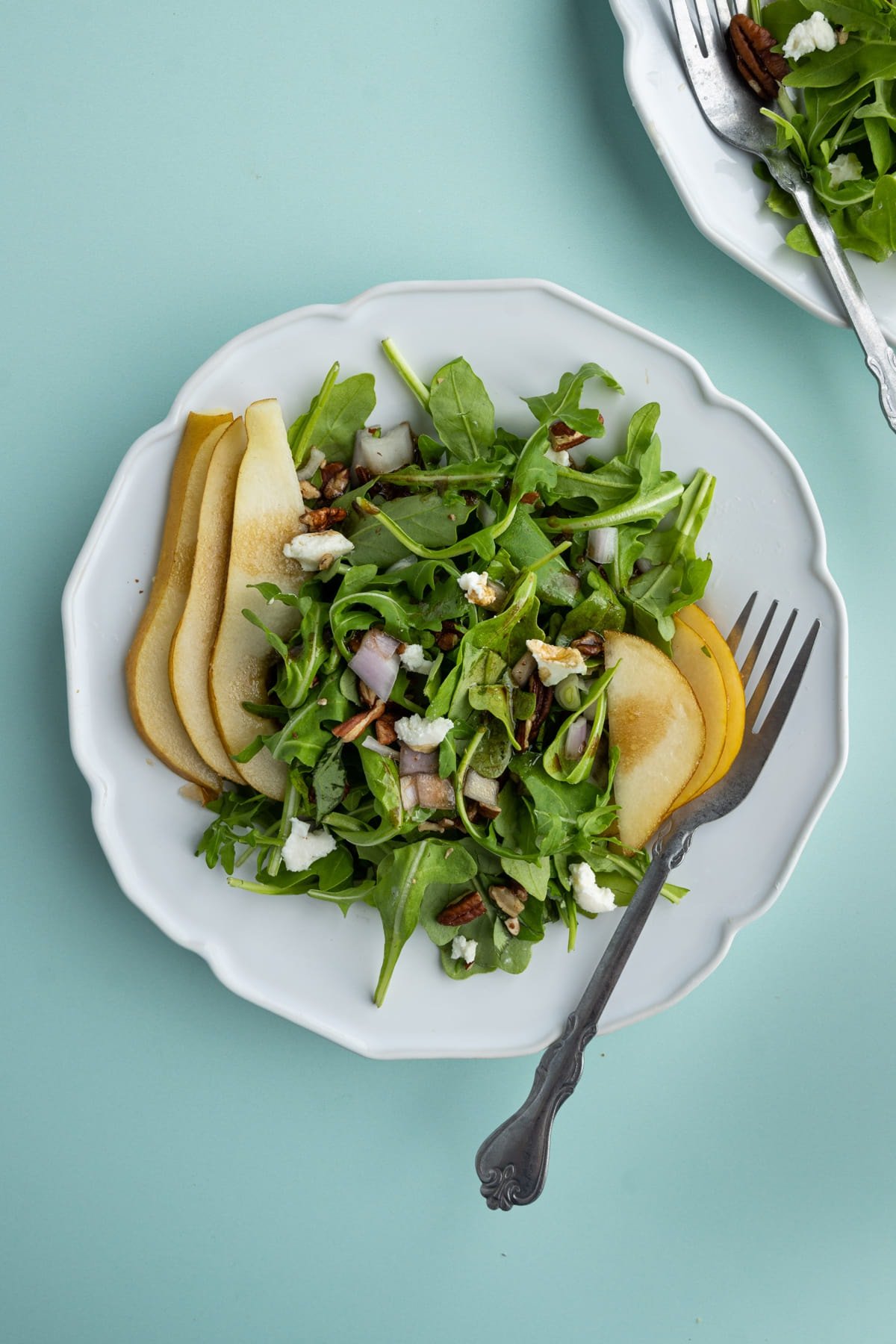 Overhead image of plated salad with sliced pear and arugula