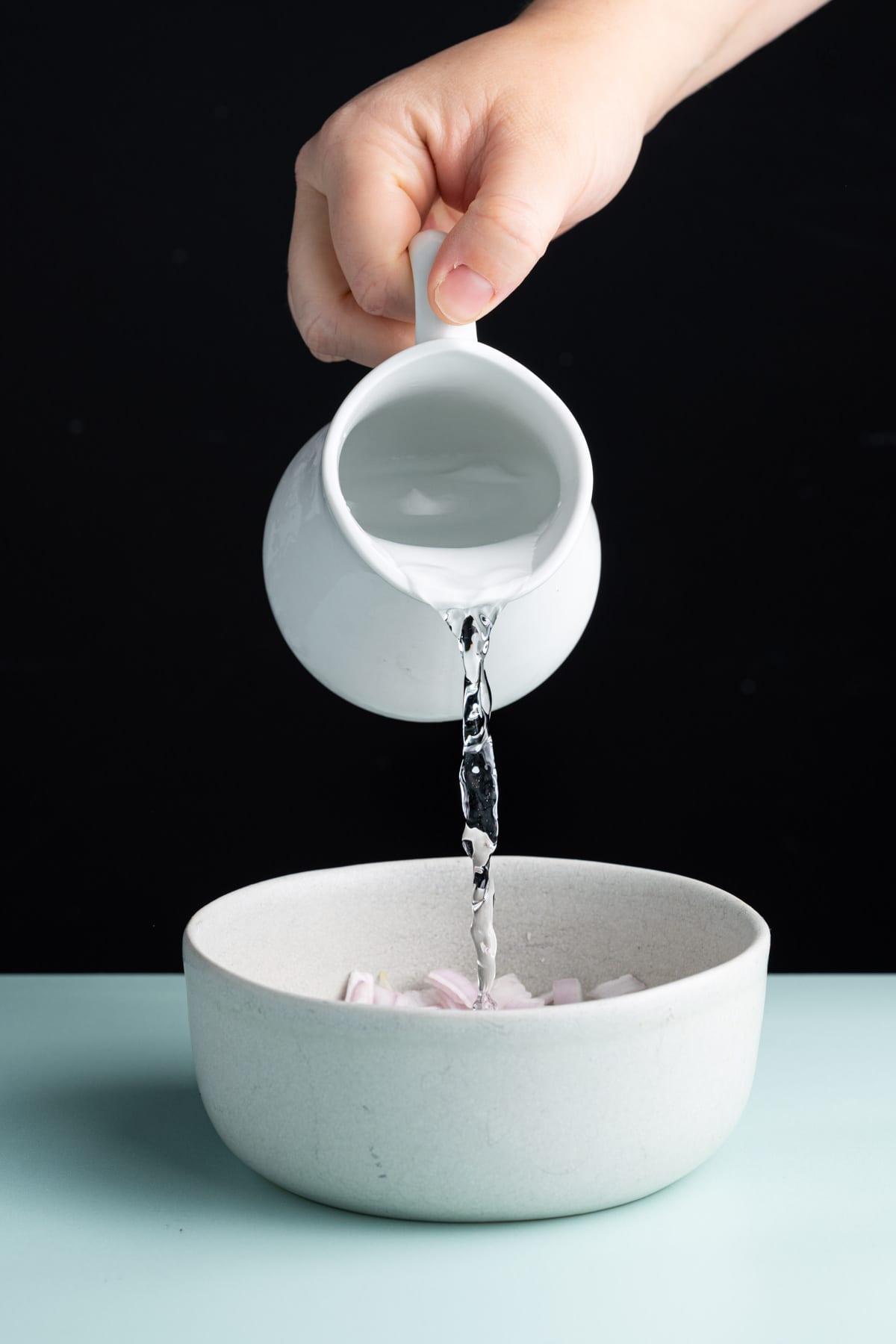 Pouring water over diced shallots to mellow their flavor slightly