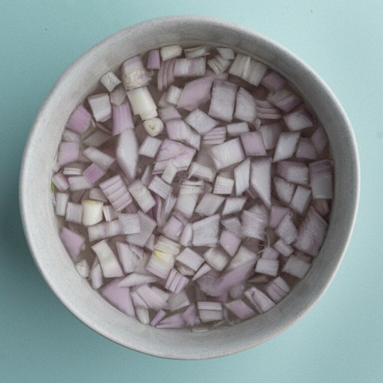 Soaking shallots in a bowl of water for 5 minutes to mellow them out