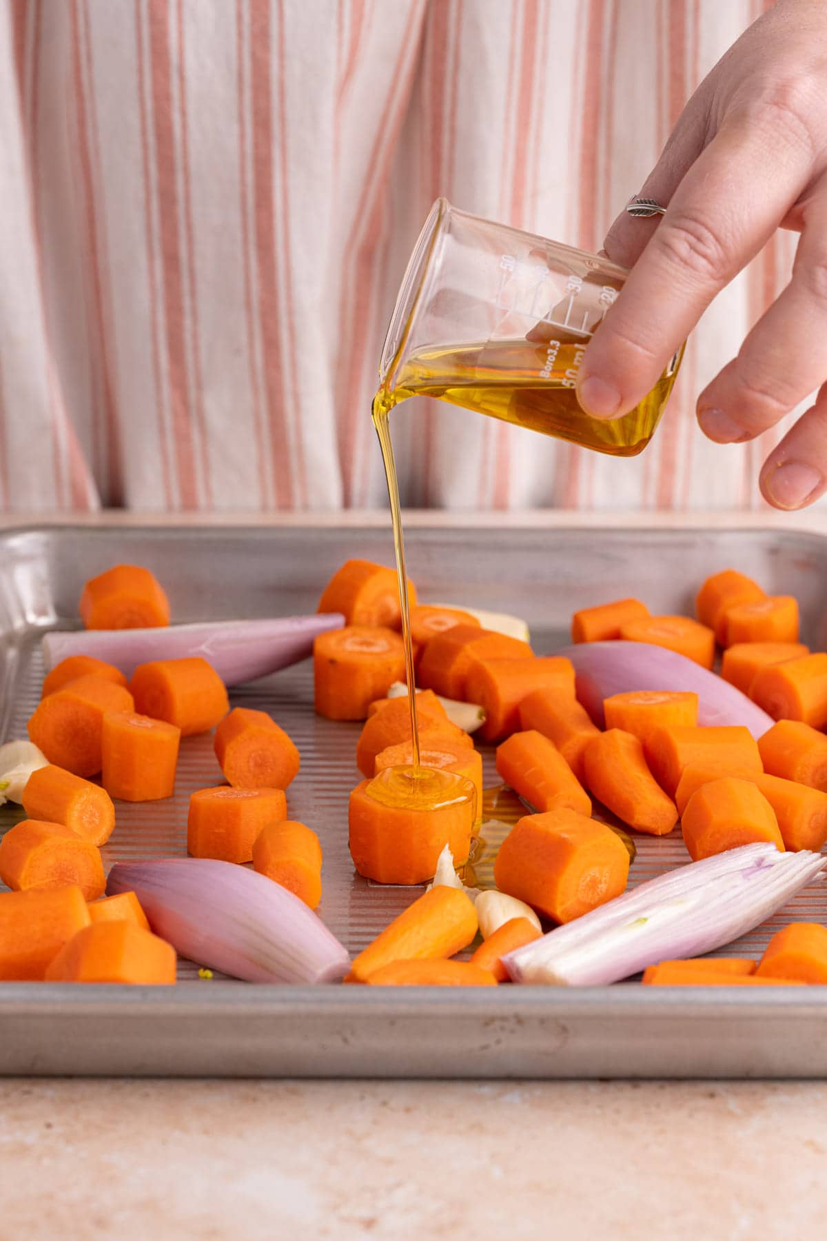 Adding olive oil to carrots to roast them