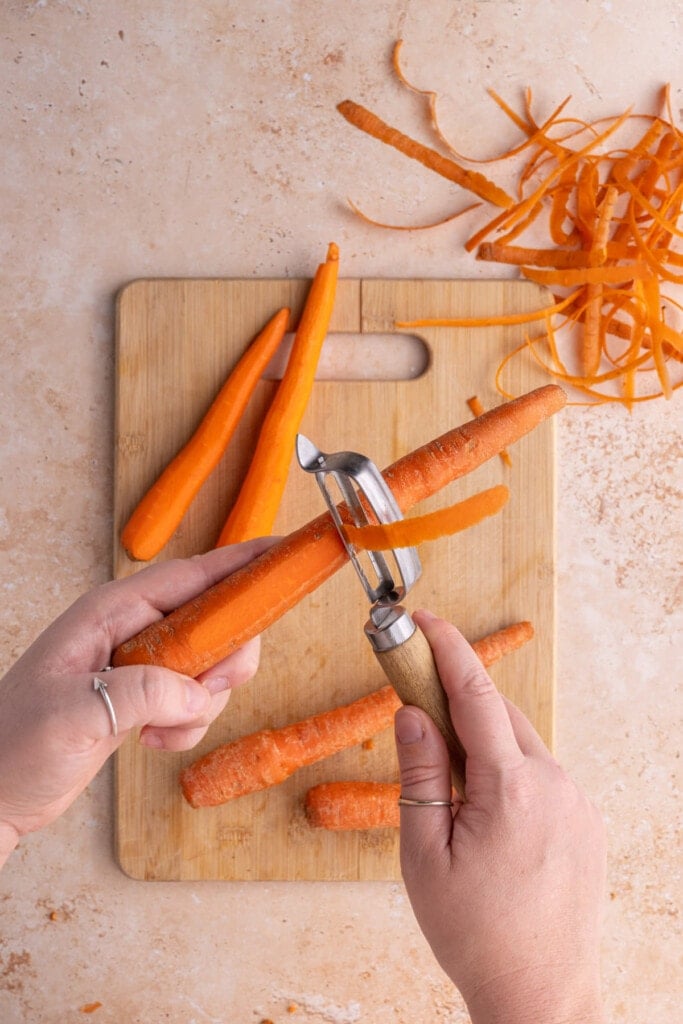 Peeling outer layer off carrot to make them more tender