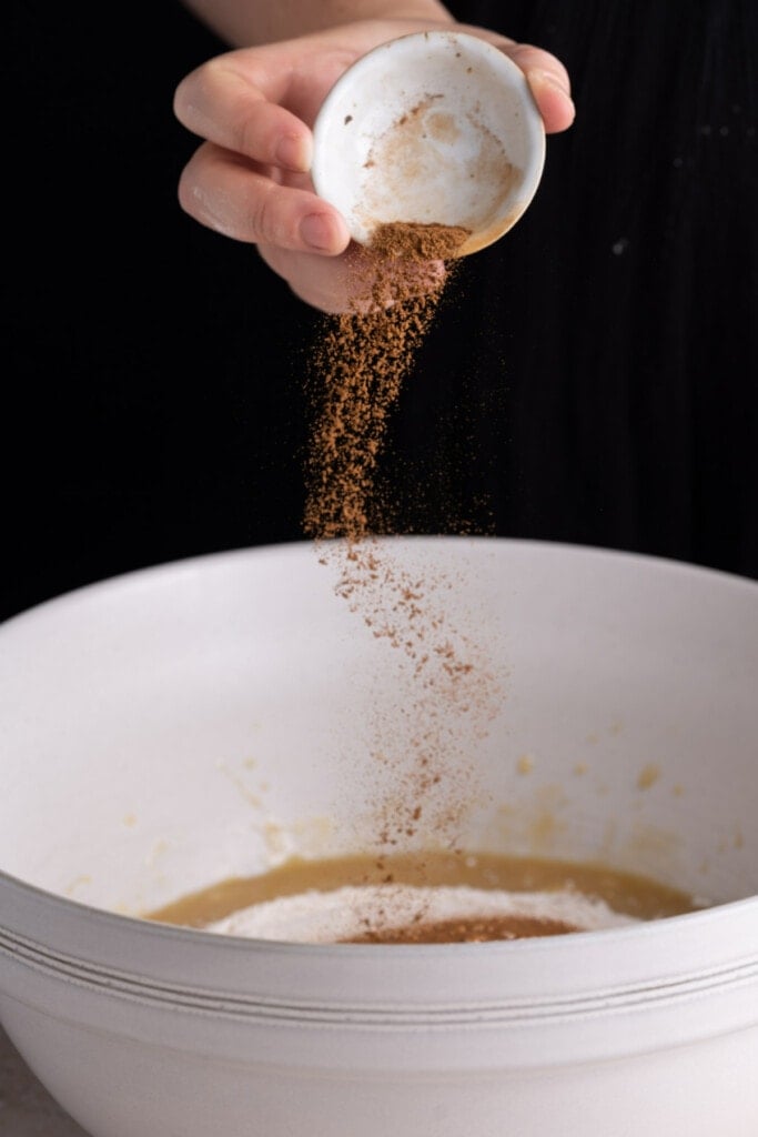 Adding cinnamon to the banana bread batter.