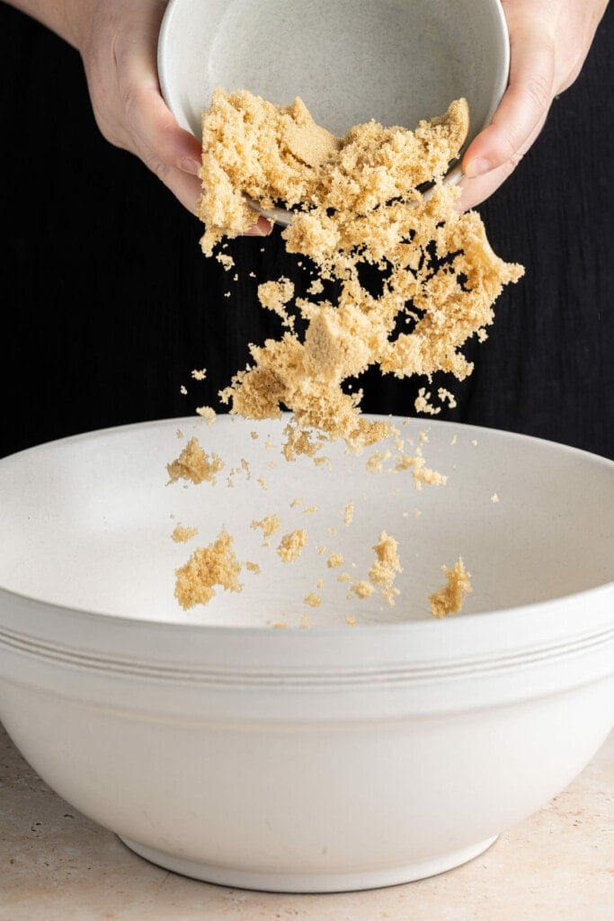 Adding brown sugar to banana bread batter.