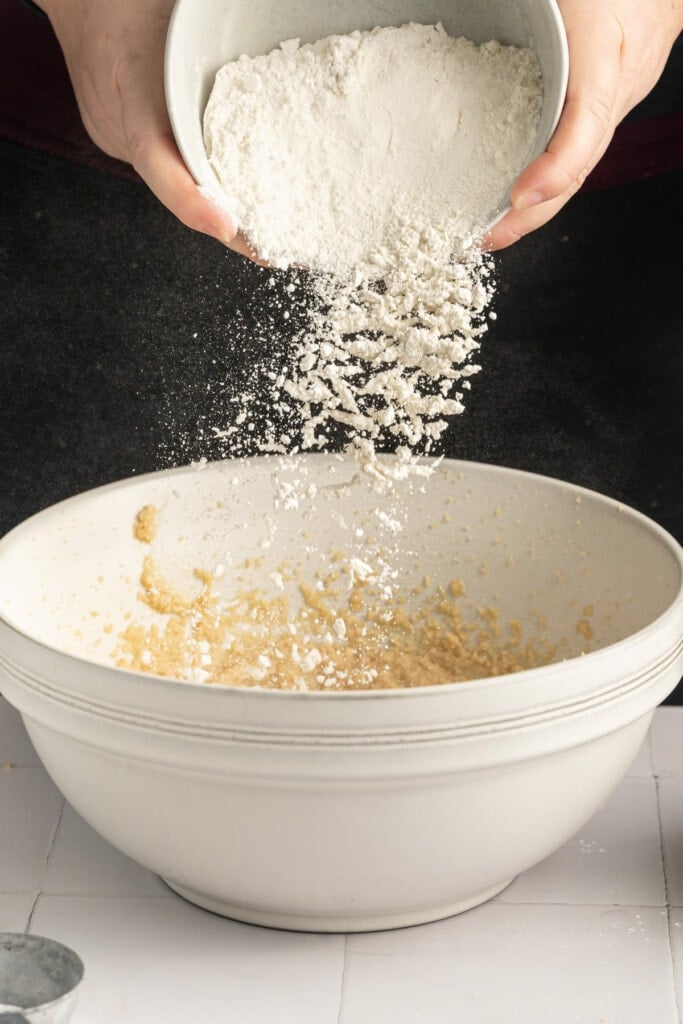 Adding all-purpose flour to chocolate chip cookie dough.