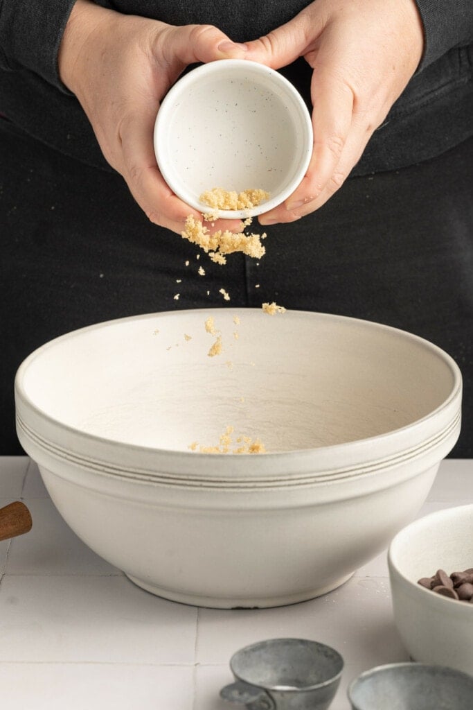 Adding brown sugar to the butter to cream them together to form cookie dough.