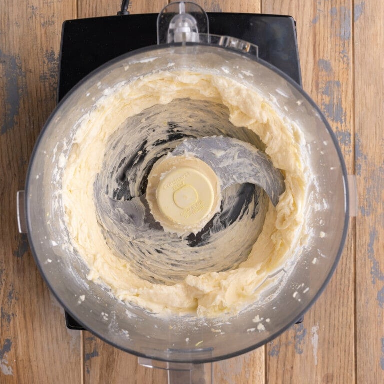 Blending unsalted softened butter, garlic salt, and minced garlic in a food processor
