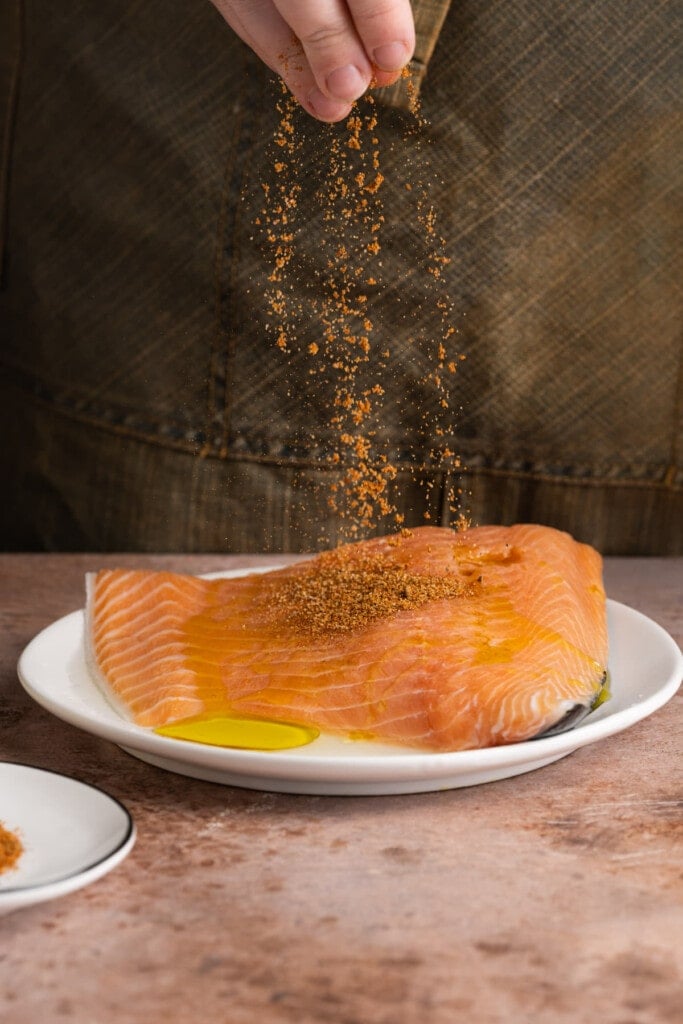 Adding Old Bay Seasoning to salmon.