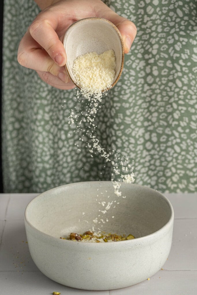Adding Parmsan cheese to pistachios to form crust for salmon.