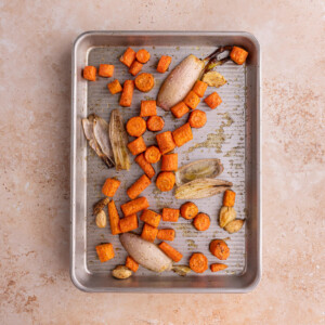 Roasted carrots, garlic, and shallots on a baking sheet