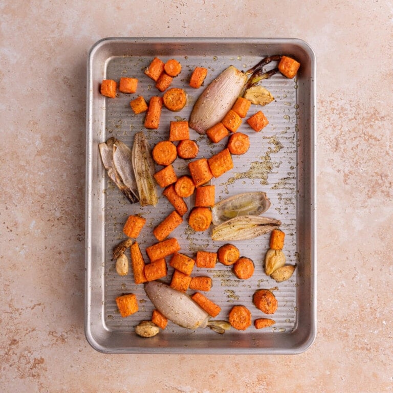Roasted carrots, garlic, and shallots on a baking sheet