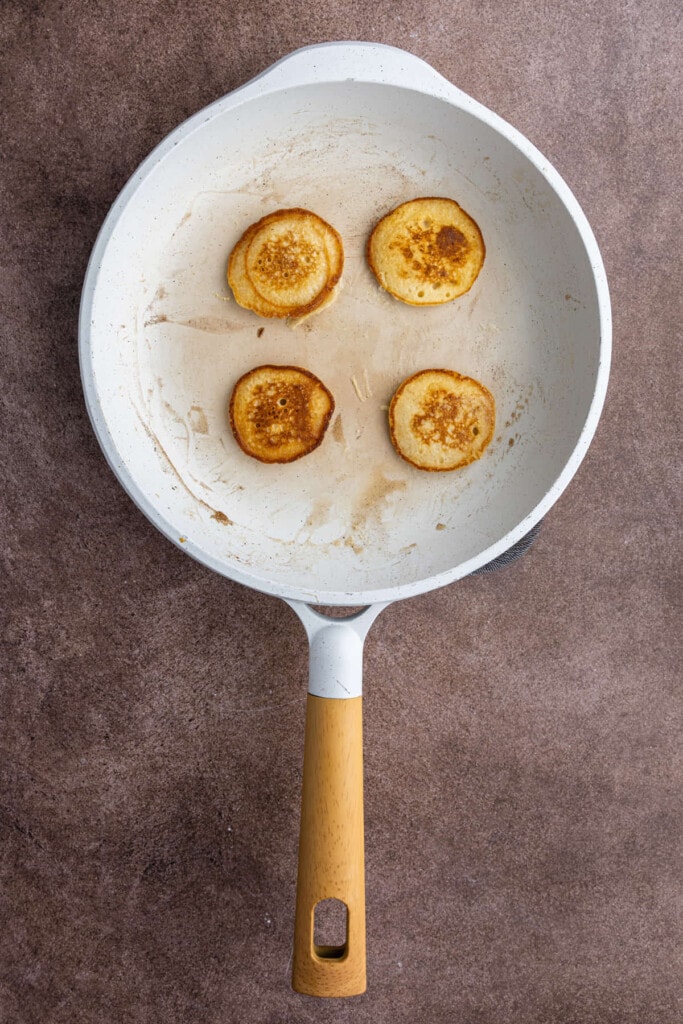 Four mini pancakes frying a pan