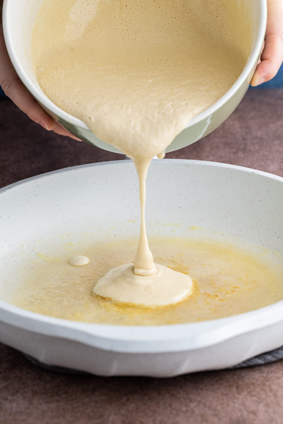 Pouring pancake batter into pan to form 2-3 inch pancakes