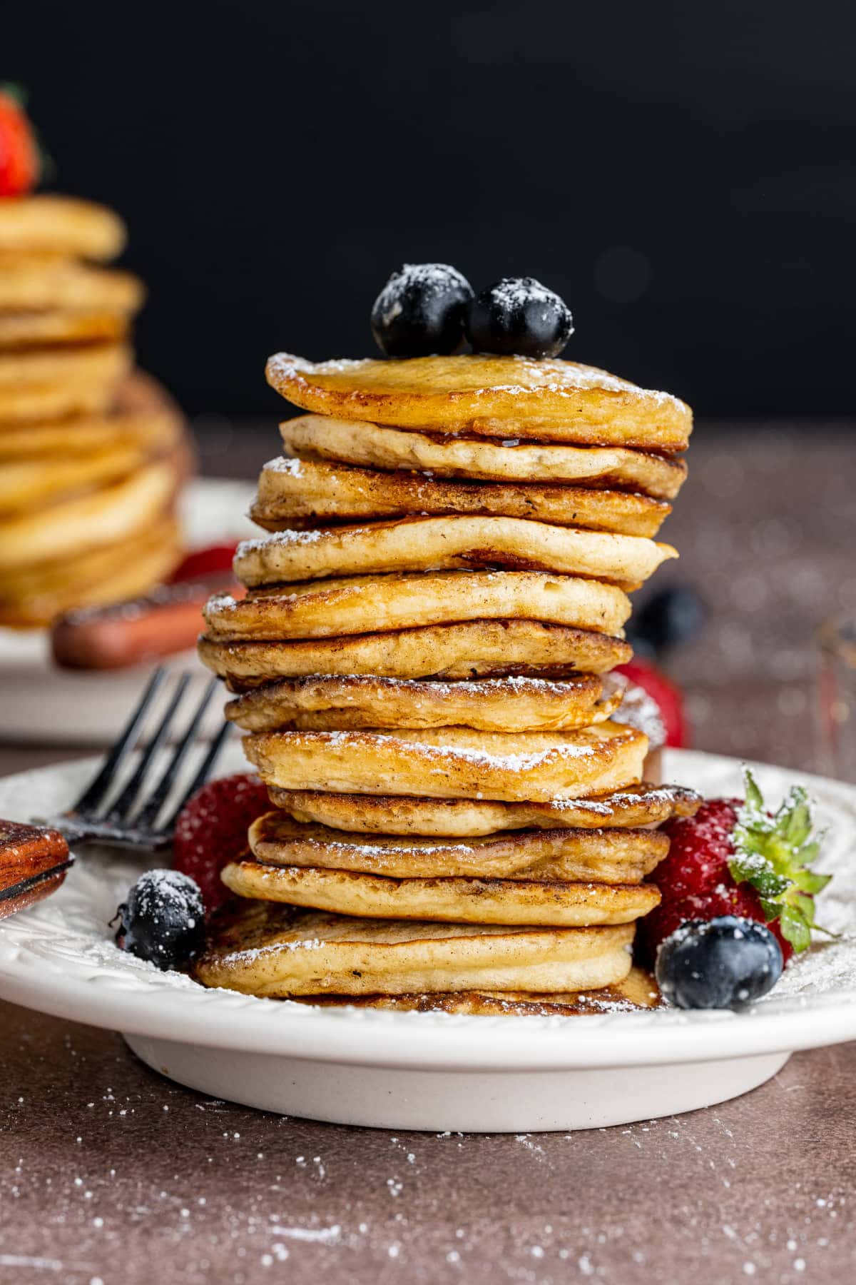 Giant stack of mini pancakes topped with fresh fruit