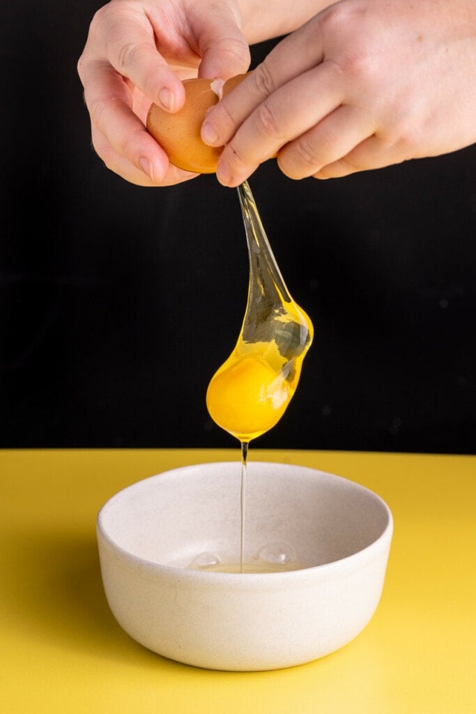 Cracking eggs into a bowl to beat them.