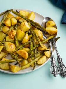 Serving platter with roasted potatoes and asparagus and serving spoons