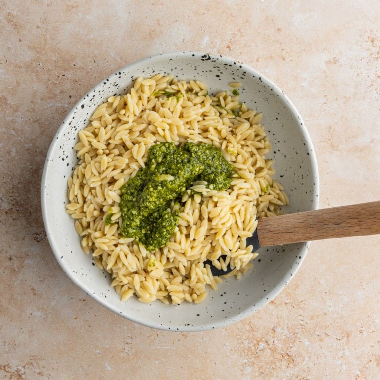 Mixing pesto and cooked orzo