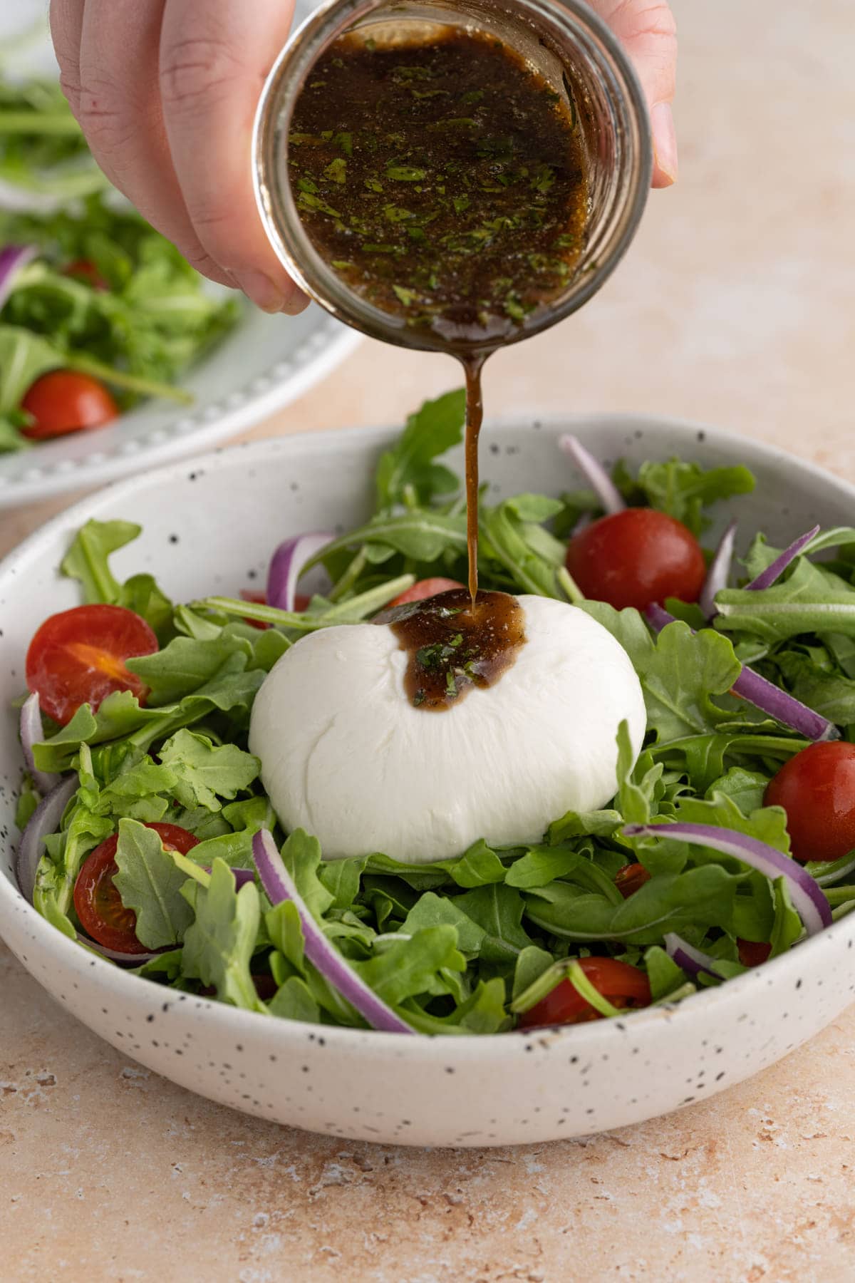 Adding homemade Basil Balsamic Vinaigrette to arugula salad