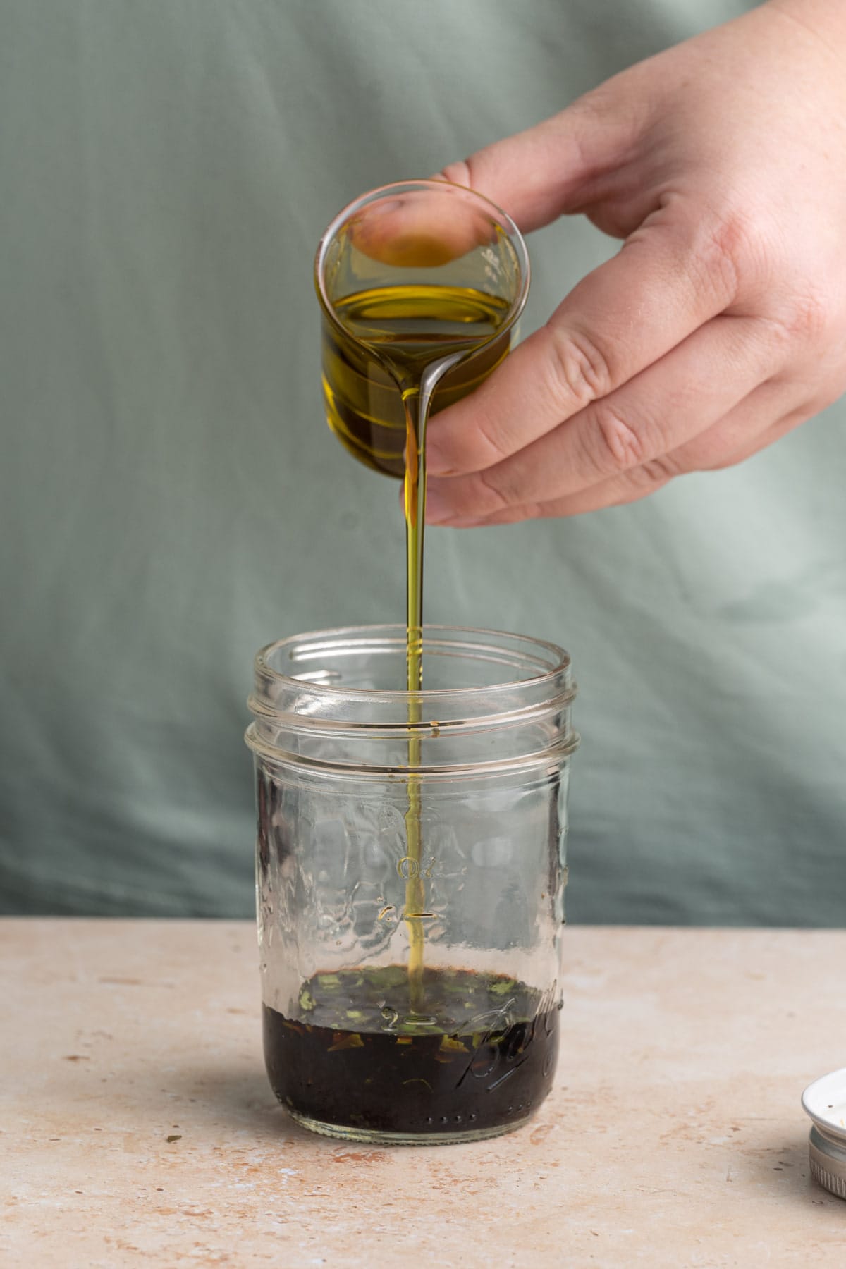 Adding vinaigrette and oil to a glass jar to shake to emulsify