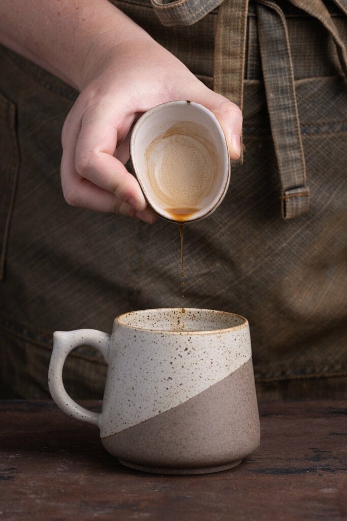 Adding vanilla extract to mug with mashed banana.
