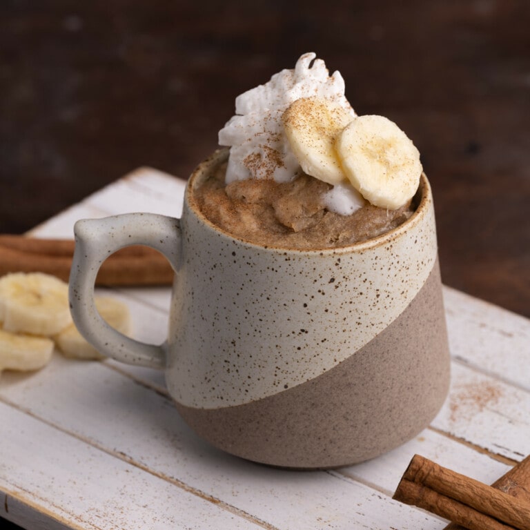 Banana Bread in a Mug topped with sliced banana and whipped cream
