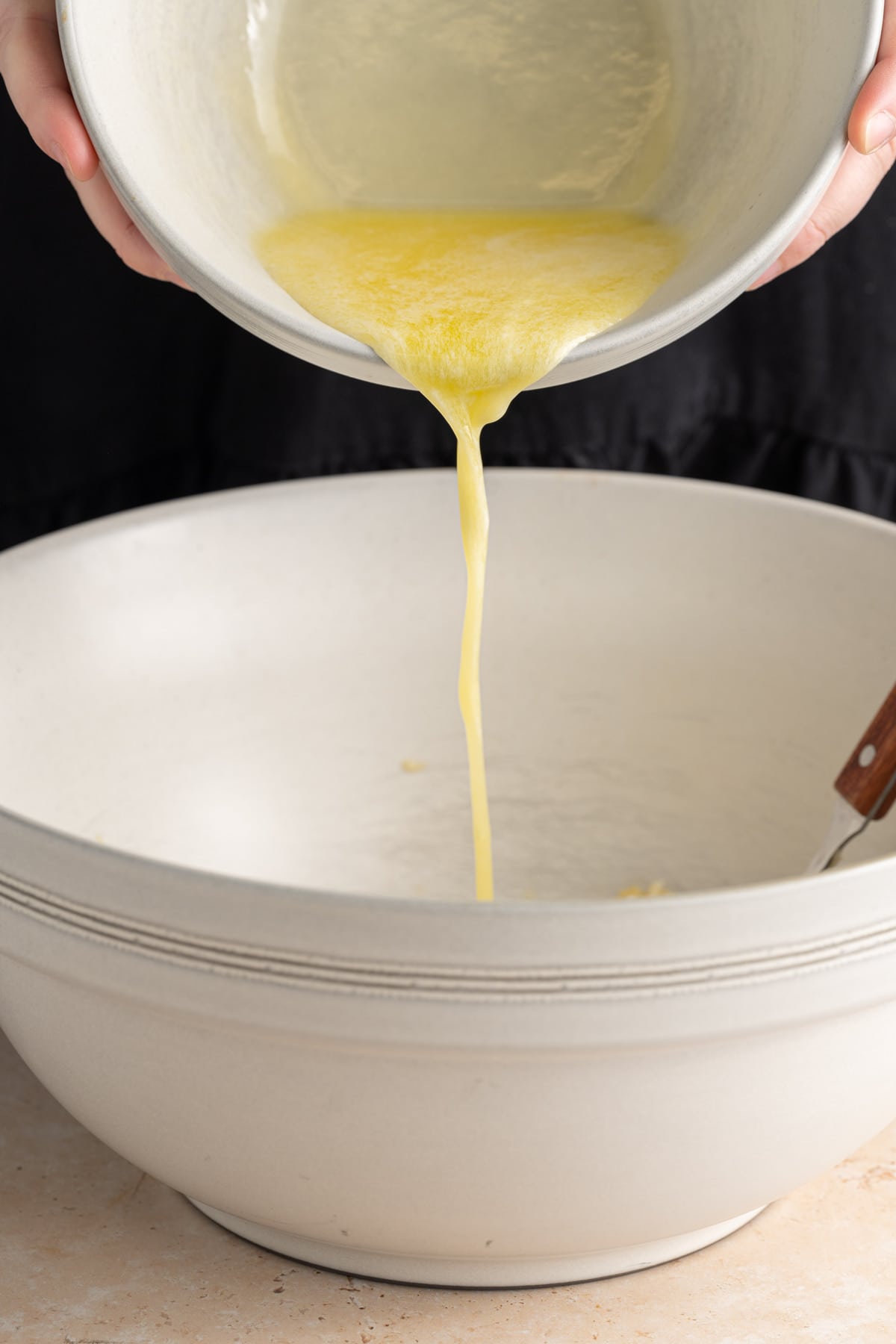 Adding melted butter to large mixing bowl with smashed banana