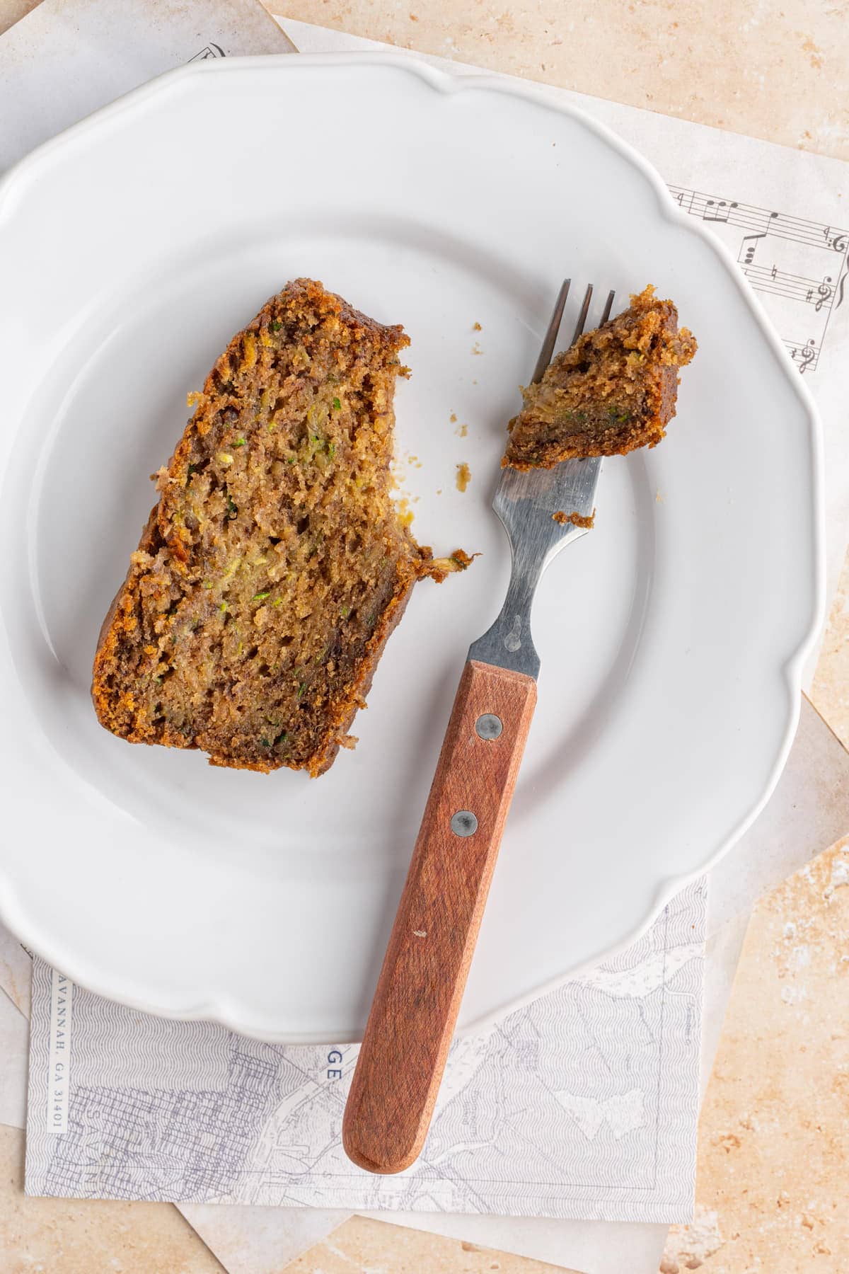 Slice of Zucchini Banana Bread on white plate with forkful taken out