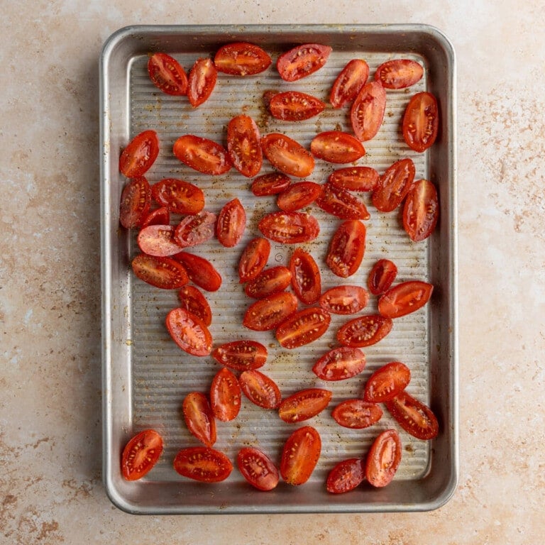 Baking sheet with grape tomatoes tossed in oil, salt, and pepper