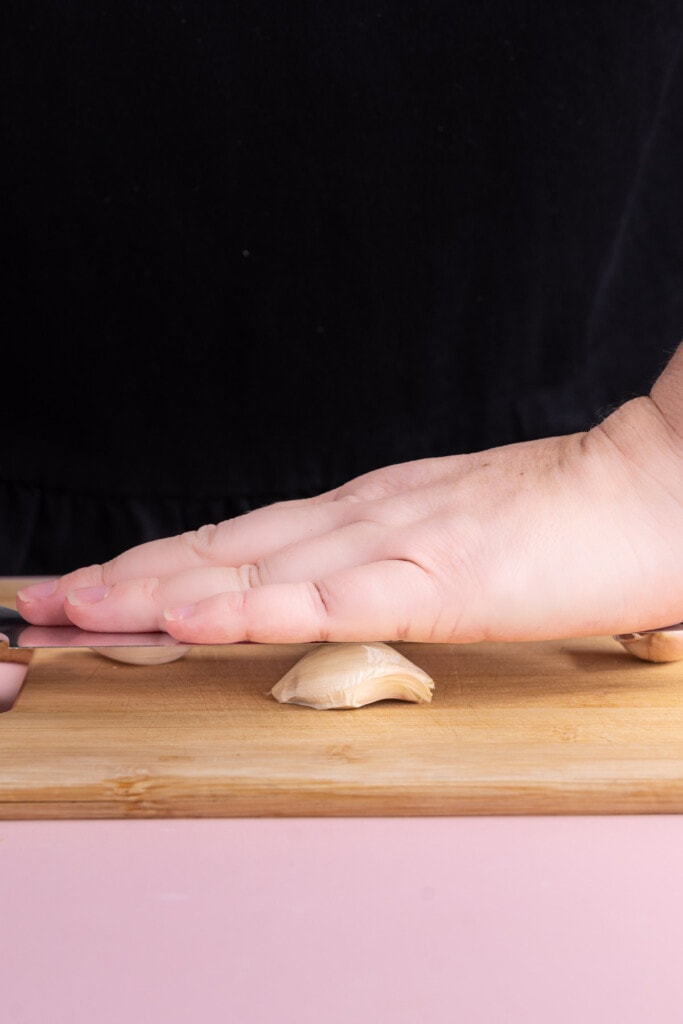 Crushing garlic with the smooth side of a knife