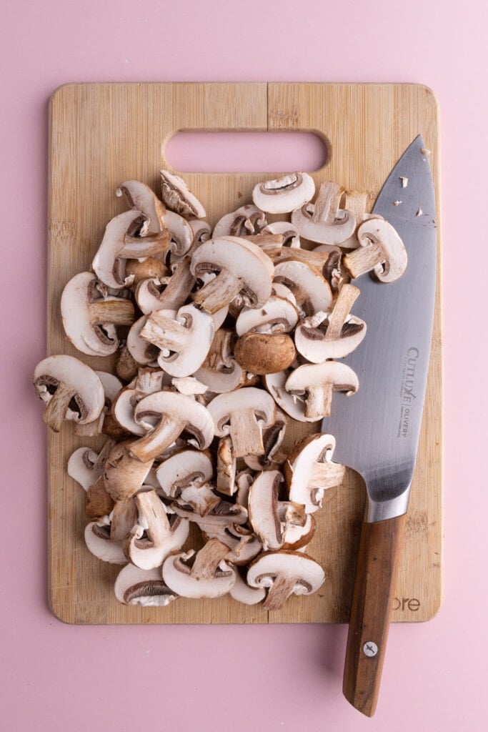 Cleaned and sliced mushrooms on a chopping board.