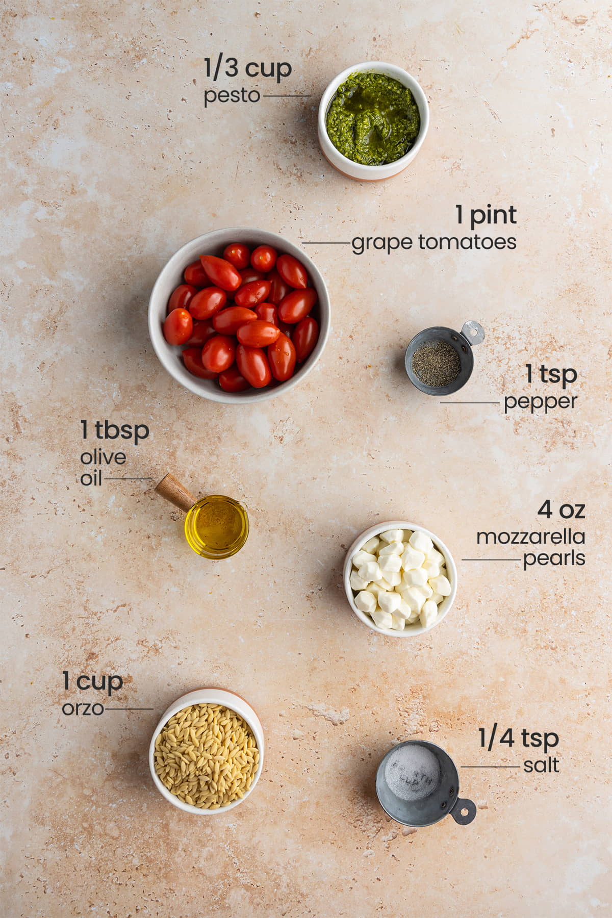 ingredients for orzo pesto salad - pesto, grape tomatoes, pepper, olive oil, mozzarella pearls, orzo, salt