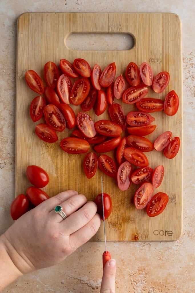 Slicing grape tomatoes in half lengthwise.