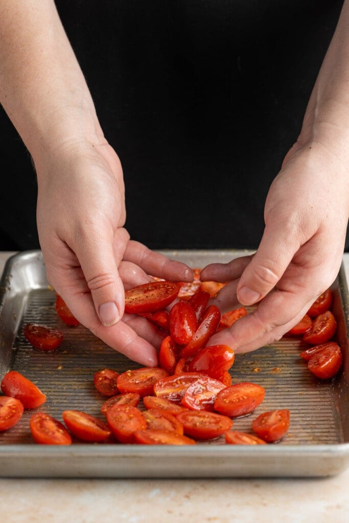 Tossing grape tomatoes in olive oil, salt, and pepper.