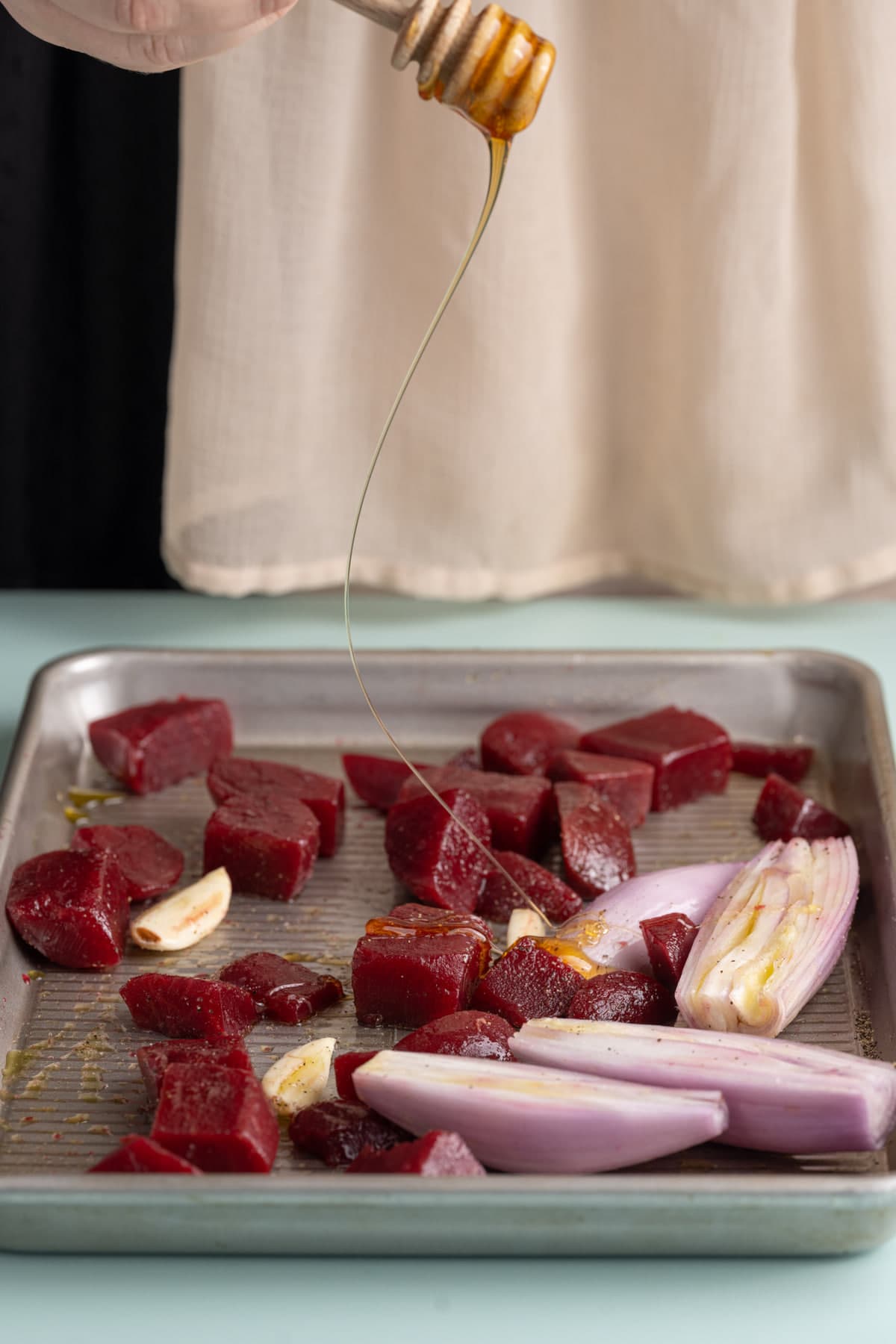 Adding honey to beets, shallots, and garlic to roast