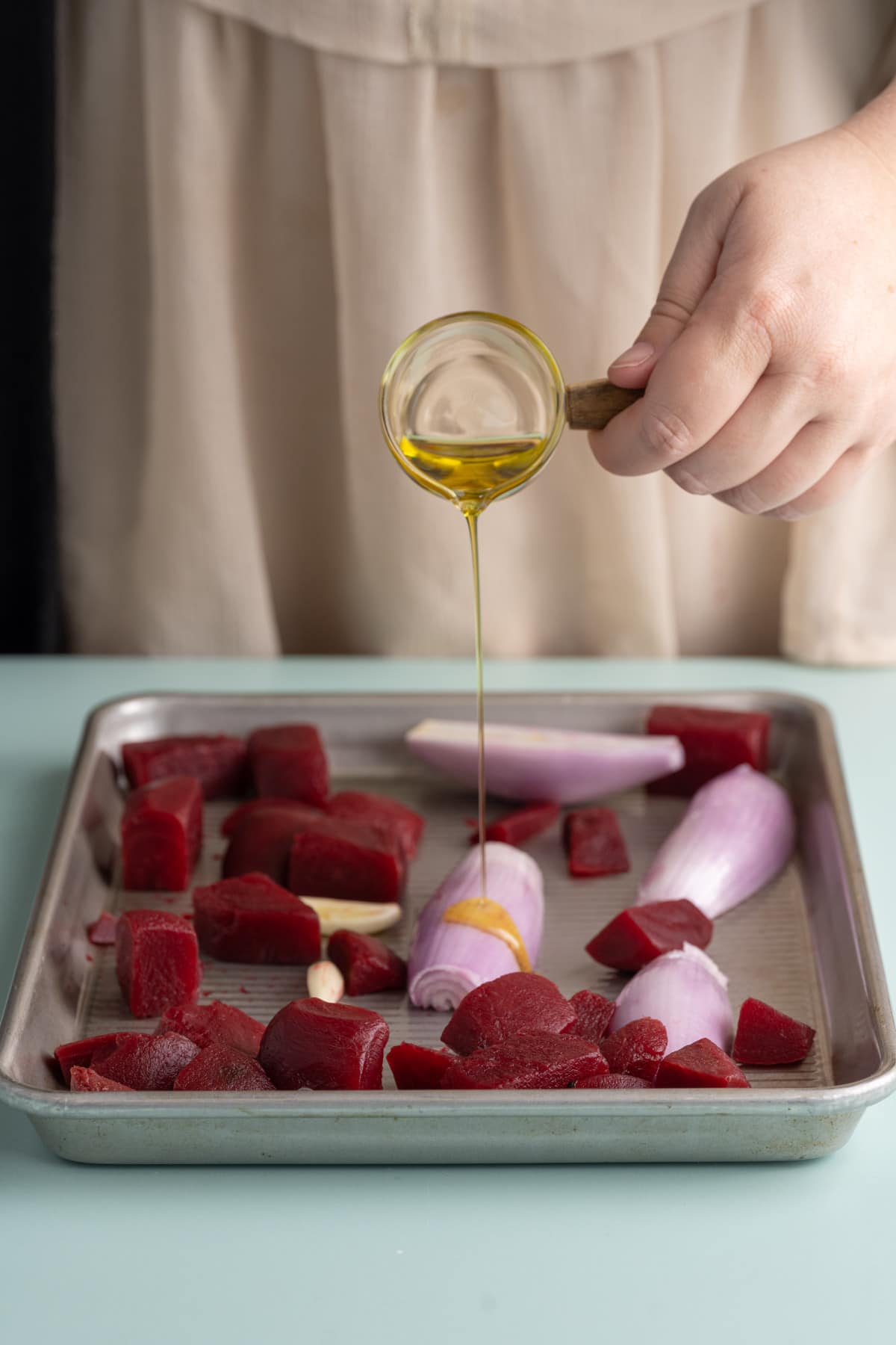 Adding olive oil to beets, shallots, and garlic to roast