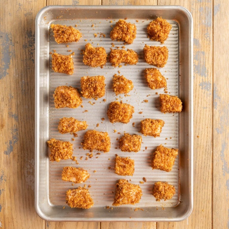 Salmon nuggets lined up on a baking sheet ready for the oven