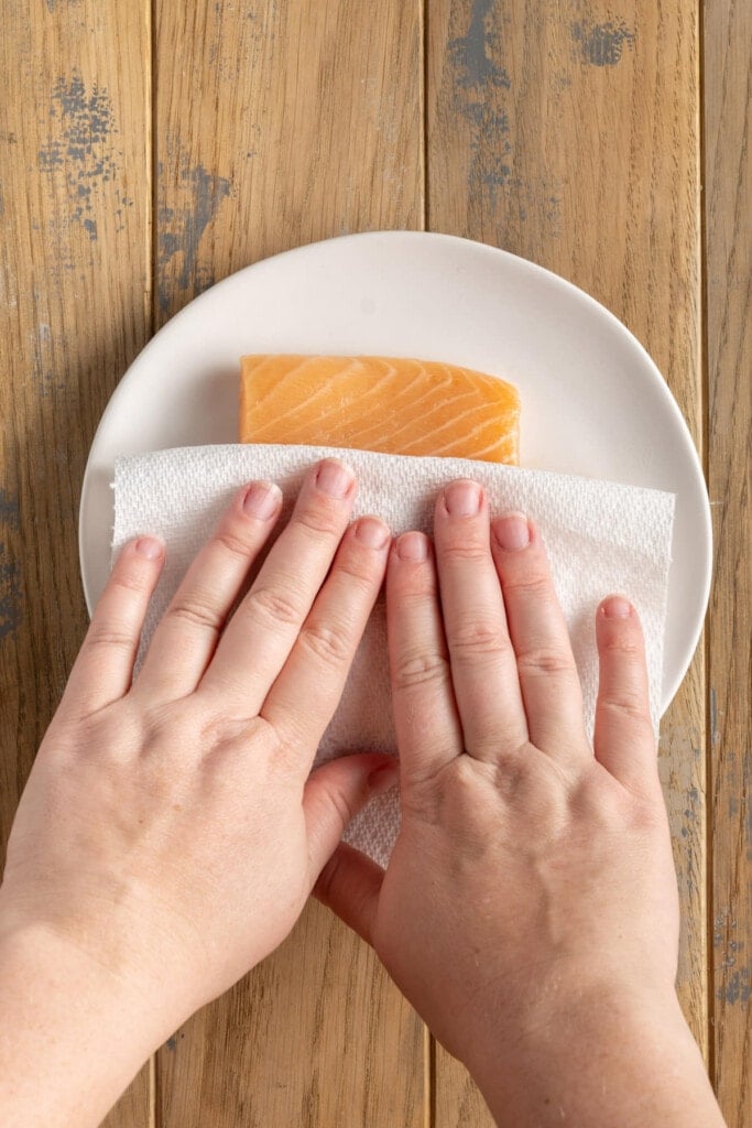 Patting salmon dry before coating in breading.