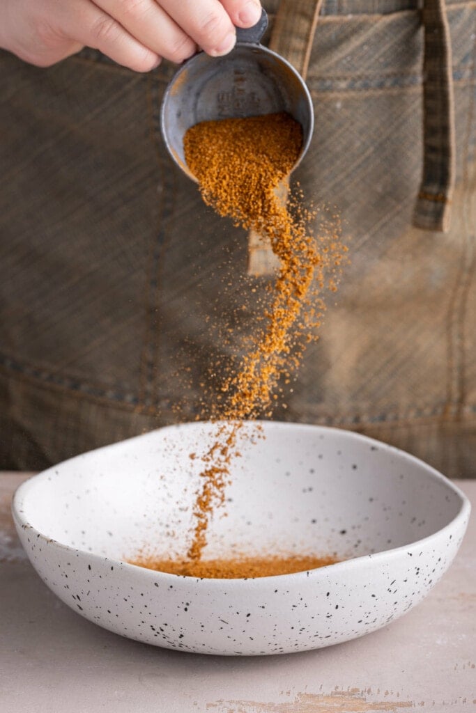 Adding Cajun seasoning to a shallow bowl