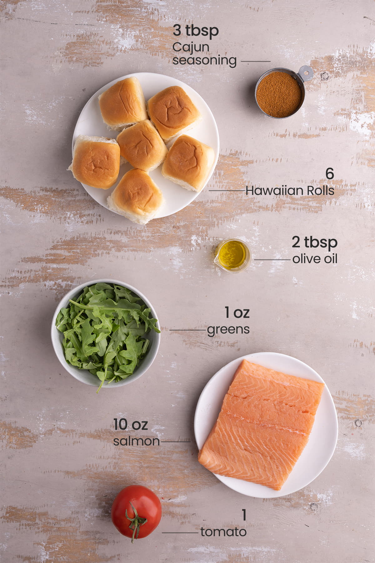 ingredients for salmon sliders - Cajun seasoning, Hawaiian rolls, olive oil, greens, salmon, tomato