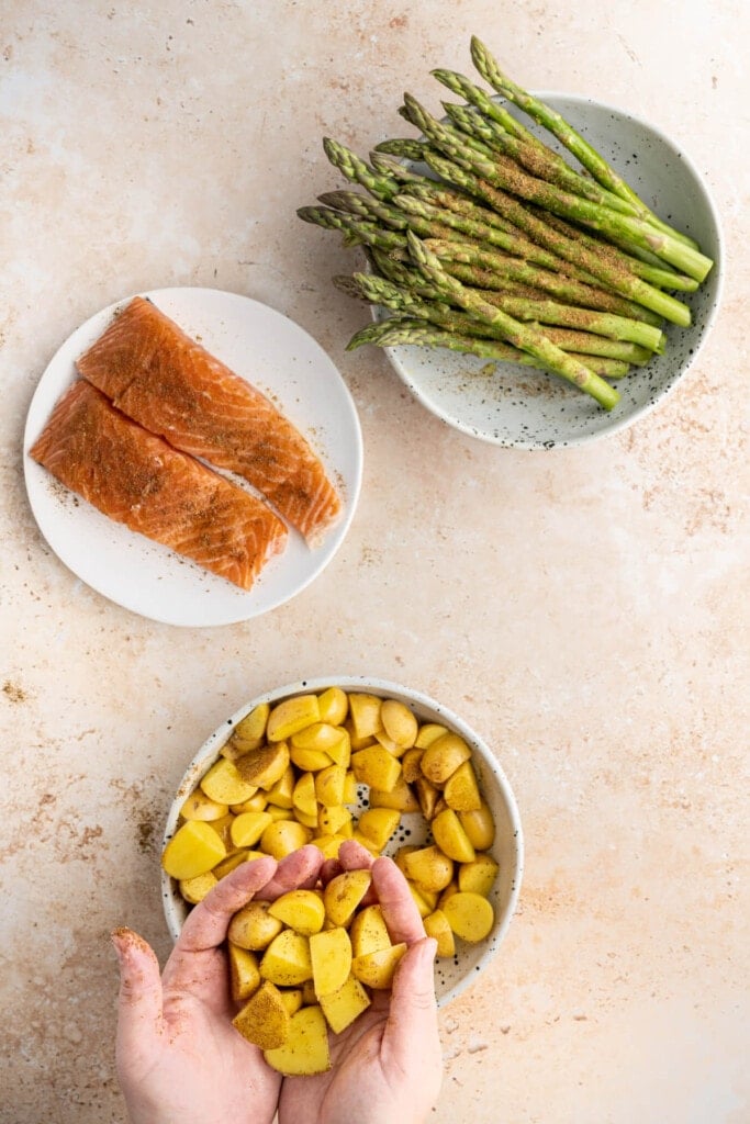 Adding Old Bay Seasoning to veggies and fish and tossing to coat.