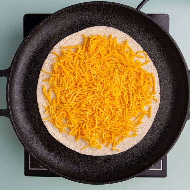 Add even layer of cheese to a flour tortilla