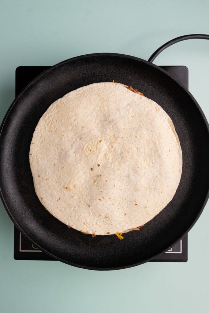 Finishing quesadilla assembly by adding second tortilla