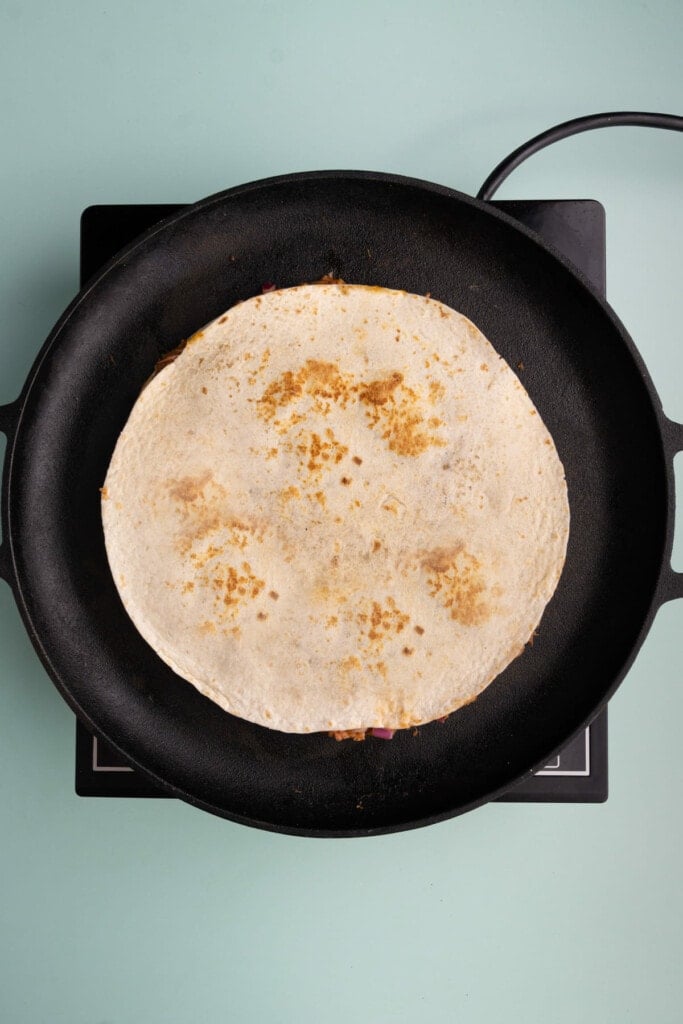 Cooking quesadilla until golden brown on both sides.