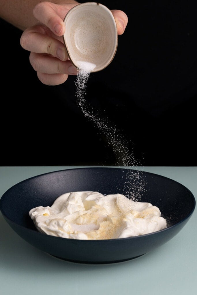 Adding seasoning to Caramelized Onion Dip.