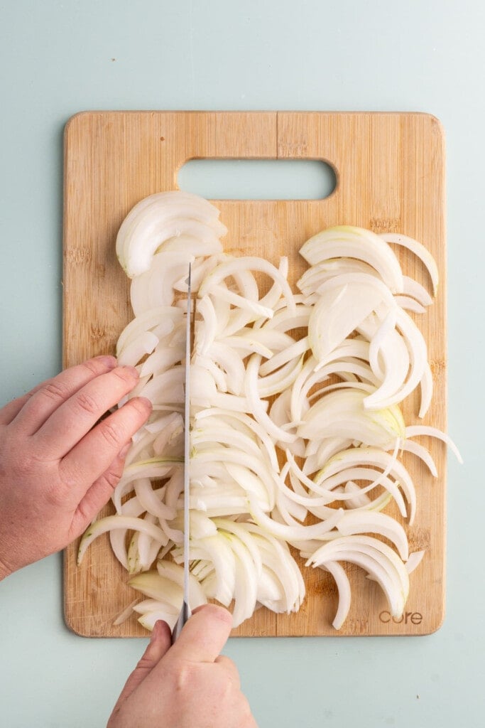 Chopping long slices of onion into smaller pieces