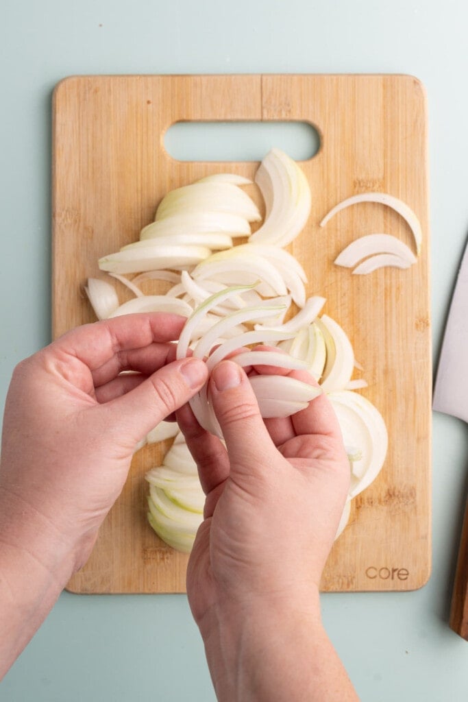 Using hands to peel apart layers of sliced onion