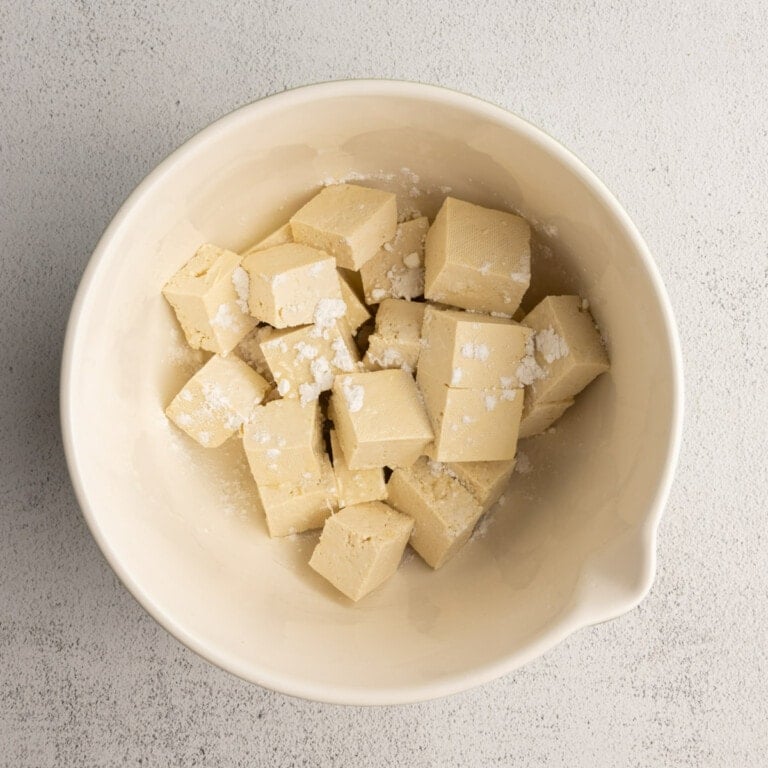 Tossing cubed tofu in cornstarch and olive oil