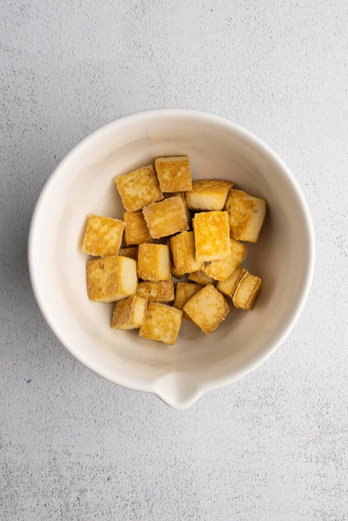 Crispy baked tofu in a large mixing bowl